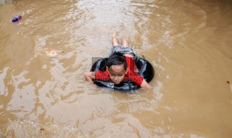  Anak-anak bermain di genangan air di Kampung Poncol, Kelurahan Bukit Duri, Kecamatan Tebet, Jakarta Selatan, Senin (24/12). (Republika/Prayogi)