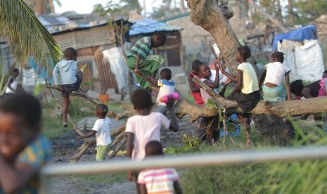 Anak-anak bermain di sebuah pohon yang tumbang setelah dihempas badai Idai di Beira, Mozambik, Rabu (27/3).  