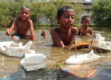 Anak-anak bermain mainan kapal terbuat dari styrofoam di kubangan bekas genangan air rob di Kalibaru, Jakarta Utara, Rabu (22/2). (Republika/Aditya Pradana Putra)