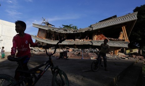 Anak-anak bermain sepeda di halaman Masjid yang runtuh akibat gempa tektonik di Desa Meuko Kuthang, Kecamatan Bandar Dua, Kabupaten Pidie Jaya, Aceh, Kamis (8/12). 