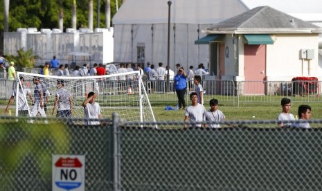 Anak-anak imigran bermain di luar kantor job Corps yang kini menjadi kediaman mereka, Senin (18/6), di Homestead Florida. Tidak diketahui apakah anak-anak yang melintas perbatasan tidak ditemani dewasa atau dipisahkan dari anggota keluarganya.