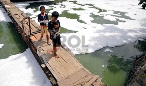   Anak-anak melintasi jembatan Kali Sunter yang dipenuhi busa dari Rumah Pompa Sunter Selatan, Jakarta Utara, Rabu (27/11).   (Republika/Prayogi) 