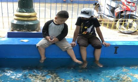 Anak-anak memanfaatkan kolam terapi ikan di Perkampungan Budaya Betawi, Situ Babakan, Kecamatan Jagakarsa, Jakarta Selatan. 