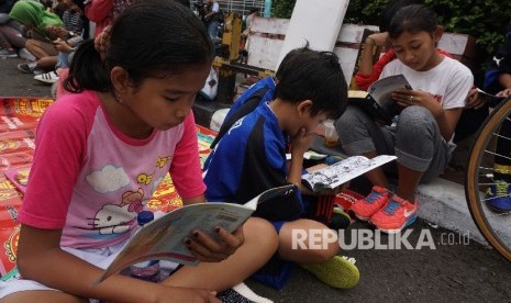  Anak-anak membaca buku di stand komunitas Buku 100 Desa saat berlansungya Car Free Day di Bundaran HI, Jakarta, Ahad (2/4). 