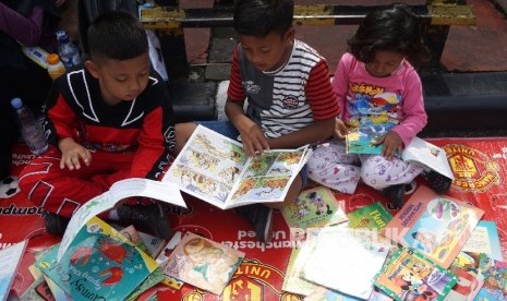  Anak-anak membaca buku di stand komunitas Buku 100 Desa saat berlansungya Car Free Day di Bundaran HI, Jakarta, Ahad (2/4). 