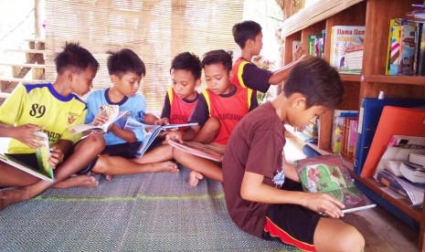 Anak-anak membaca di perpustakaan Bale Tau, Desa Batukaras, Kecamatan Cijulang, Kabupaten Pangandaran.