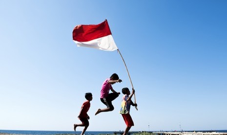 Anak-anak membawa bendera merah putih di desa pesisir pulau Ndao, Rote, Nusa Tenggara Timur, Kamis (13/8). 