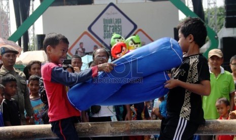  Anak-anak mengikuti lomba gebuk bantal dalam hiburan rakyat 