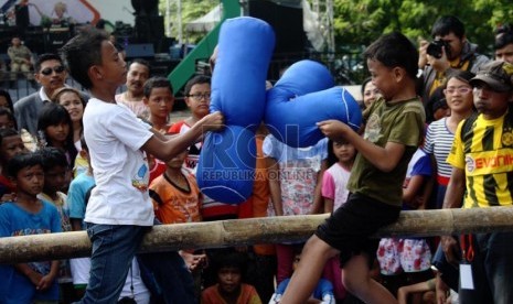  Anak-anak mengikuti lomba gebuk bantal dalam hiburan rakyat 