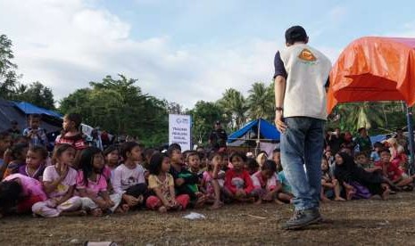 Anak-anak pengungsi menyaksikan dongeng yang dikisahkan oleh Mujani (29) dari Gerakan Pada Pendongeng untuk Kemanusiaan (Geppuk) di lapangan yang dijadikan Posko Pengungsian Desa Wombo Kalonggo, Tanantovea, Donggala, Sulawesi Tengah (Sulteng).