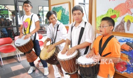 Anak-anak sindroma down sedang bermain alat musik.