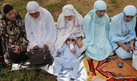   Anak balita minum susu disamping ibunya saat pelaksanaan shalat Idul Fitri di Manila, Filipina, Ahad (19/8). (Cheryl Ravelo/Reuters)