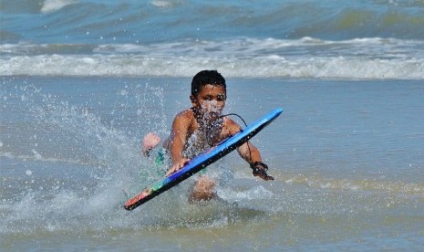 Anak berenang dengan boogie board di laut/ilustrasi.