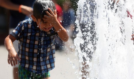 Anak bermain dengan air saat hawa sangat panas di Santiago, Cile.