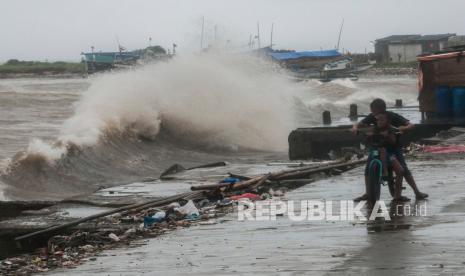 Anak bermain di sekitar jalan yang rusak akibat diterjang gelombang di Labuan, Pandeglang, Banten, Sabtu (27/11/2021). Badan Meteorologi Klimatologi dan Geofisika (BMKG) mengeluarkan peringatan dini adanya potensi gelombang tinggi mencapai 4 meter di perairan Selat Sunda yang terjadi hingga 28 November 2021.