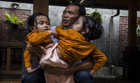 Anak kembar siam Al Putri Dewi Ningsih dan Al Putri Anugrah digendong oleh ayahnya di Bandung, Jawa Barat, Senin (30/8/2021). Putri dan Dewi yang berusia delapan tahun tersebut datang bersama keluarga ke Kota Bandung dari Garut untuk melakukan pemeriksaan kesehatan dan pengukuran pembuatan kursi roda khusus yang mampu membantu mereka beraktivitas dan sekolah.