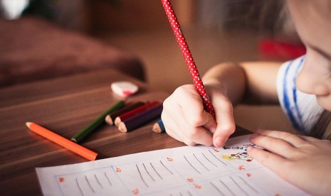 Anak menulis. Menulis atau mencatat kembali hasil pembelajaran di buku tulis tetap penting dilakukan selama pembelajaran jarak jauh.