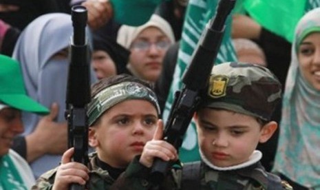 Anak Palestina memegang senjata mainan dalam acara peringatan hari jadi Hamas ke-24 di Gaza City pada Rabu (14/12). 