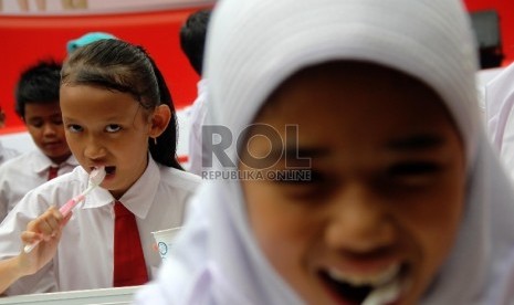 Anak sekolah menyikat gigi.