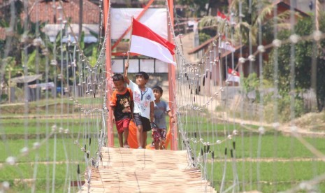 Anak warga Sumedang Selatan membawa bendera Merah Putih di Jembatan Harapan.