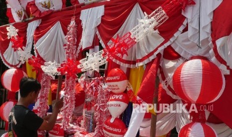 Andi pedagang bendera merah putih dan pernak pernik 17 san, merapihkan jejeran dagangannya yang berada di gerobaknya di kisaran jalan Matraman, Jakarta, Rabu (2/8).