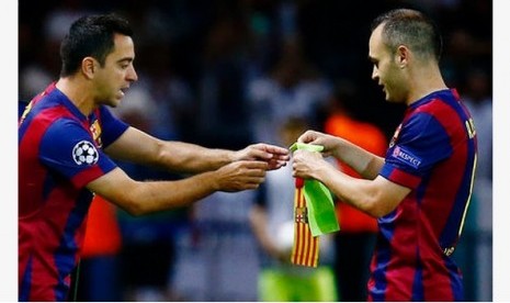 Andres Iniesta (kanan) memberikan ban kapten kepada Xavi