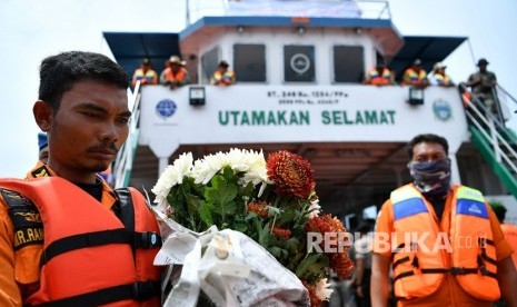 Anggota Basarnas memegang bunga saat berlangsung prosesi tabur bunga bagi korban tenggelamnya KM Sinar Bangun di kawasan titik tenggelamnya kapal di Danau Toba, Sumatera Utara, Senin (2/7). 