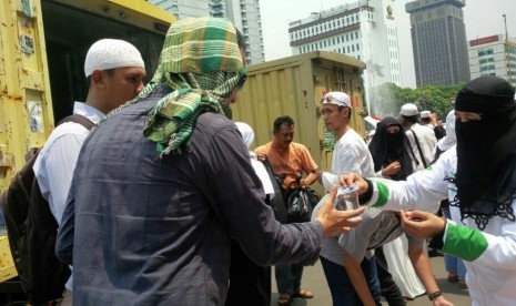 Anggota FPI, Yuni, membagikan nasi bungkus kepada pendemo usai shalat Jumat di Bundaran Patung Kuda, Jumat (4/11).