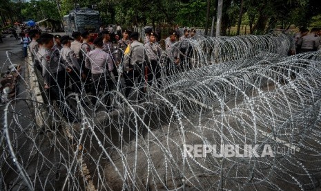 Anggota Kepolisian di depan pagar berduri saat sidang Penistaan Agama berlangsung di Auditorium Kementerian Pertanian, Jakarta Selatan, Selasa (10/1)