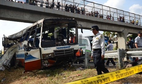 Anggota kepolisian melakukan identifikasi bus yang mengalami kecelakaan di Km 202 Tol Palikanci, Ciperna, Jawa Barat, Selasa (14/7).  (Republika/Raisan Al Farisi)