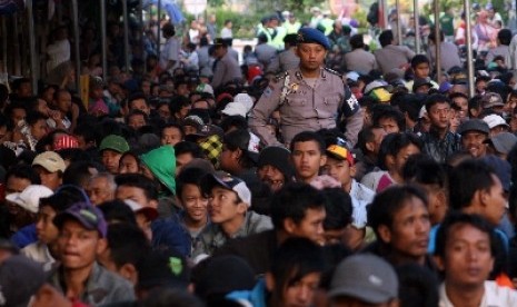 Anggota kepolisian melakukan penjagaan belasan ribu warga yang antre dalam pembagian sedekah di pabrik PT Gudang Garam Tbk, Kediri, Jawa Timur.