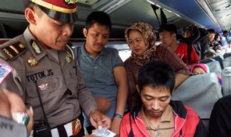 Anggota kepolisian memeriksa tanda pengenal dan barang bawaan penumpang bus di Jombang, Jawa Timur, Selasa (28/7). Menjelang pembukaan Muktamar ke-33 Nahdlatul Ulama (NU) di Jombang pada 1-5 Agustus 2015 pihak kepolisian setempat memperketat pengamanan gun