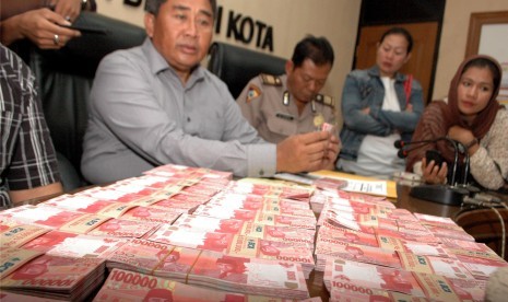 Aparat kepolisian menunjukkan barang bukti uang palsu pecahan Rp 100 ribu yang banyak beredar .