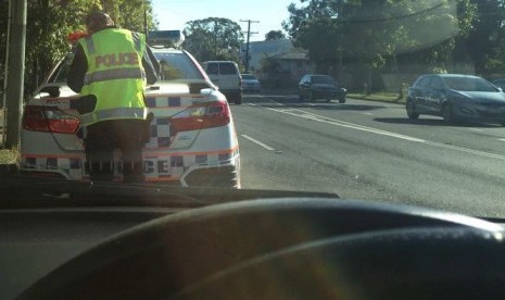 Anggota Kepolisian Queensland saat menemukan pelanggaran di jalan raya.