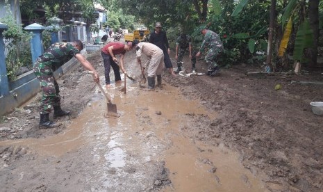 Anggota Kodim 0616/Indramayu bersama warga bergotong royong membersihkan lumpur yang menutupi jalan Desa Plumbon, Kecamatan/Kabupaten Indramayu, Kamis (11/4). Memasuki hari keempat, banjir luapan sungai Cimanuk mulai surut di sejumlah lokasi, namun  meninggalkan lumpur dan kotoran. 