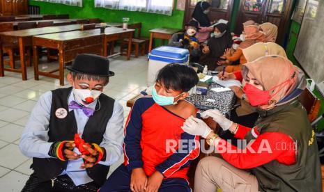 Anggota Komunitas Badut Tasikmalaya (Battik) memainkan sulap di depan anak saat vaksinasi COVID-19 Sinovac di SDN Argasari, Kota Tasikmalaya, Jawa Barat, Jumat (21/1/2022). Vaksinasi bagi anak usia 6-11 tahun bersama badut sulap itu untuk menarik minat mereka agar bersedia mengikuti vaksinasi untuk mencapai kekebalan komunal. 