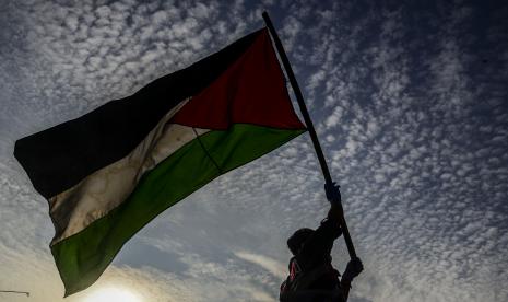 Anggota komunitas Bagi Indonesia mengibarkan bendera Palestina saat melakukan aksi penggalangan dana di kawasan Karet, Jakarta.