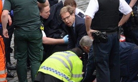 Anggota parlemen dari partai konservatif Tobias Ellwood saat mencoba menyelamatkan polisi korban penusukan di luar gedung parlemen Inggris di London, Rabu (22/3).