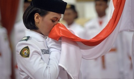 Anggota Pasukan Pengibar Bendera Pusaka (Paskibraka) Nasional 2016 asal Sulawesi Barat Ade Yuliana mencium bendera Merah Putih saat upacara pengukuhan yang dipimpin Presiden Joko Widodo di Istana Negara, Jakarta, Senin (15/8). 