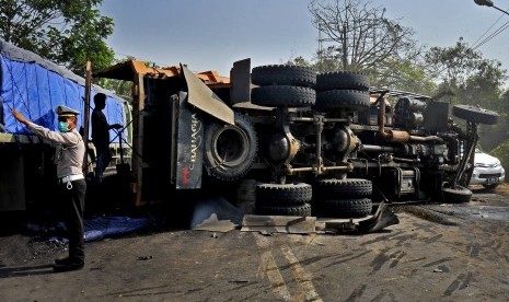 Anggota Polantas mengatur arus kendaraan di dekat truk terguling akibat tabrakan beruntun (ilustrasi)