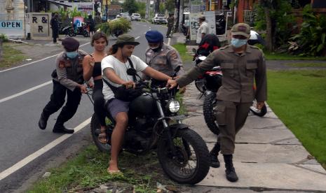 Anggota Polisi dan Satpol PP Kabupaten Badung menghentikan warga negara asing (WNA) yang melanggar protokol kesehatan saat operasi penertiban prokes dalam Pemberlakuan Pembatasan Kegiatan Masyarakat (PPKM) skala mikro di Desa Canggu, Badung, Bali, Jumat (25/6/2021). Tim satgas gabungan menindak sebanyak 18 orang WNA yang berasal dari berbagai negara tersebut untuk memberikan efek jera agar menerapkan protokol kesehatan dalam upaya pencegahan penyebaran varian baru COVID-19 di kawasan pariwisata itu.