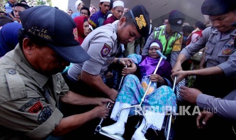 Anggota polisi membantu jemaah calon haji saat pemberangkatan ke embarkasi di kantor Pemda Bogor, Jabar, Selasa (1/8). 