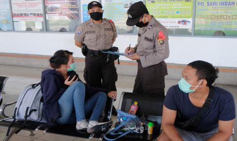 Anggota polisi mendata warga yang akan mudik saat Operasi Ketupat Agung 2020 di Terminal Mengwi, Badung, Bali, Jumat (24/4/2020). Kegiatan tersebut untuk memberikan pembinaan dan penyuluhan kepada masyarakat supaya memahami kebijakan pemerintah terkait larangan mudik dan menghindari kerumunan guna mengurangi risiko penyebaran COVID-19. 