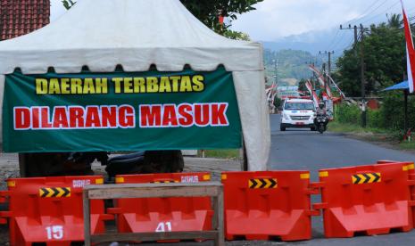 Anggota polisi mengawal mobil ambulans di jalan masuk Pondok Pesantren. Penyekatan jalur menuju pondok pesantren diberlakukan pascakebijakan karantina massal guna mencegah penyebaran COVID-19 di klaster pondok pesantren. (ilustrasi)