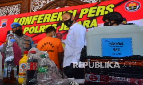 Anggota Polisi menunjukkan miras oplosan dan seorang tersangka saat rilis kasus di Polres Jepara, Jawa Tengah, Senin (7/2/2022). Kepolisian setempat berhasil mengungkap kasus penjualan miras oplosan yang menewaskan sembilan orang dan menetapkan seorang penjual miras sebagai tersangka dengan ancaman hukuman 15 tahun penjara. 