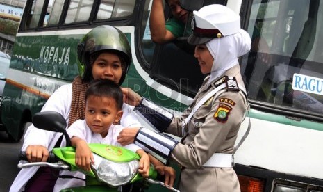   Anggota polwan Bripka Novi dengan mengenakan seragam polisi berjilbab menyapa pengendara motor di lampu merah Bundaran HI, Jakarta Pusat, Senin (25/11).  (Republika/Yasin Habibi)