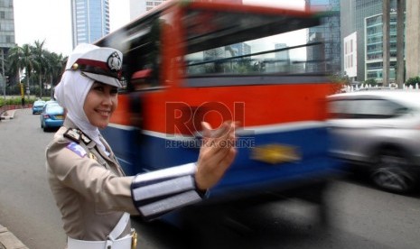  Anggota polwan Bripka Novi mengatur lalu lintas dengan mengenakan seragam polisi berjilbab di lampu merah Bundaran HI, Jakarta Pusat, Senin (25/11).  (Republika/Yasin Habibi)