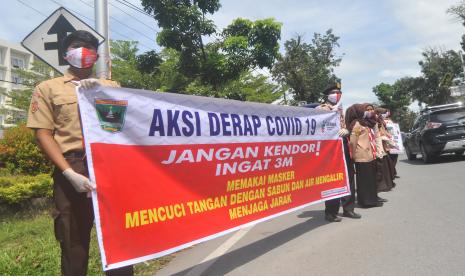 Anggota Pramuka membentangkan spanduk sosialisasi protokol kesehatan saat digelarnya Aksi Derap COVID 19, Gerakan Masyarakat Hidup Sehat di Padang, Sumatera Barat, Kamis (19/11/2020). Dinas Kesehatan Provinsi Sumatera Barat bersama Saka Bakti Husada Gerakan Pramuka Kwarcab Padang menggelar Aksi Derap COVID-19 dengan membagikan empat ribu masker dan mengkampanyekan hidup sehat agar terhindar dari virus corona baru (COVID-19).