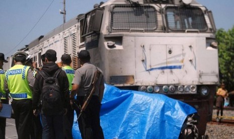 Anggota Satlantas Polres Grobogan melakukan olah TKP di lokasi berhentinya KA Argo Bromo Anggrek dan Toyota Avanza yang ringsek (ditutup terpal biru), di Stasiun Sedadi, Kecamatan Toroh, Kabupaten Grobogan, Jawa Tengah, Sabtu (20/5). Kecelakaan ini merenggut empat korban jiwa yang semuanya merupakan penumpang Toyota Avanza bernomor polisi B 1937 UZQ.