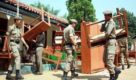  Anggota Satpol PP membereskan meja dan kursi yang dikeluarkan keluarga ahli waris pemilik lahan di SDN Jombang VII, Ciputat, Tangerang Selatan, Kamis (21/6). 